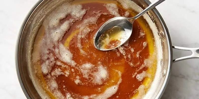 Smör som bryns och bubblar i en kastrull med sked
